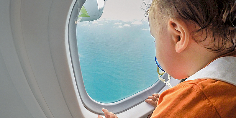 Little boy watching through window airplane