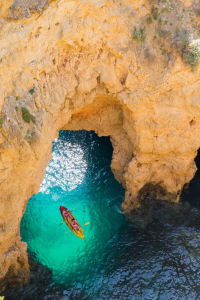 Vogelperspektive in den Eingang einer Grotte. In der Mitte ist ein Kajak zu sehen.