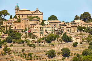 Blick auf die Terrassenstadt Valdemossa in der Region Serra de Tramuntana. Pinien und Zypressen säumen mittelalterliche Steinmauern.