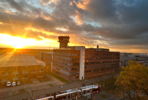 Auf dem Bild ist das Gebäude der Regionalstelle der DFS in Bremen zu sehen. Im Hintergrund geht die Sonne unter.