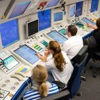 Mitarbeiter sitzen in der Radarkontrollzentrale Bremen vor Monitoren im Jahr 2024