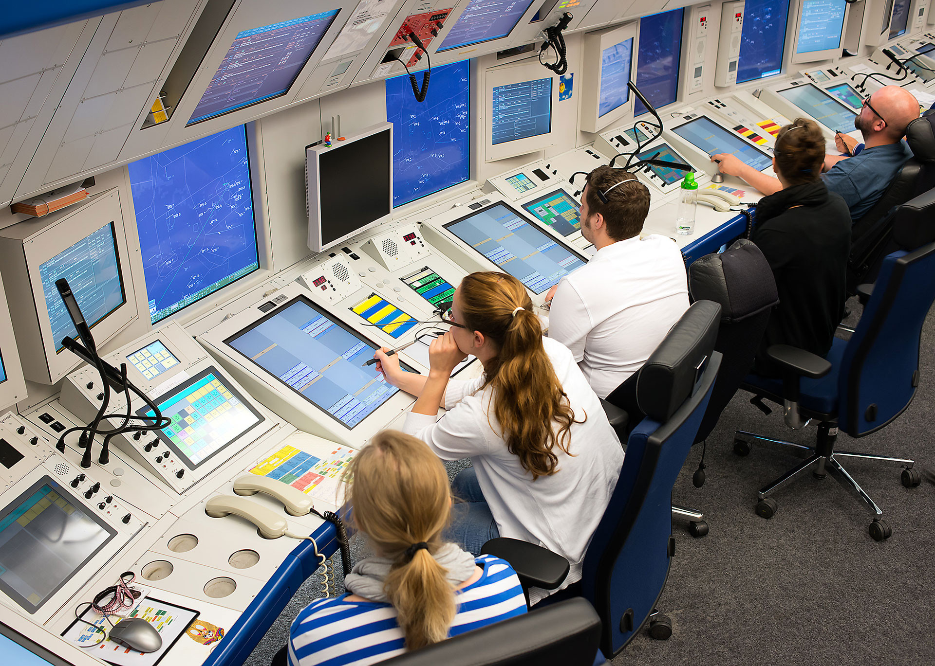 Mitarbeiter sitzen in der Radarkontrollzentrale Bremen vor Monitoren im Jahr 2024