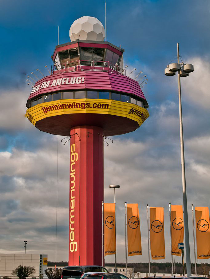 Der Tower mit der Werbung der Airline Germanwings in den Farben Brombeere, Gelb mit weißen Schriftelementen.