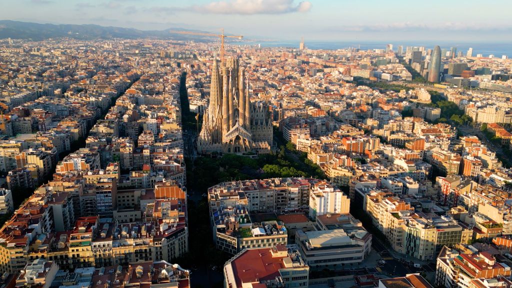 Luftaufnahme von Barcelona. Im Vordergrund ist die Basilika Sagrada Familia und im Hintergrund das Meer.