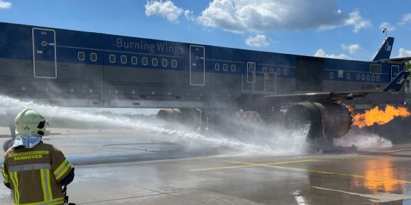 Ein Feuerwehrkollege beobachtet einen Triebwerksbrand an der Brandsimulationsanlage und den Angriff darauf.