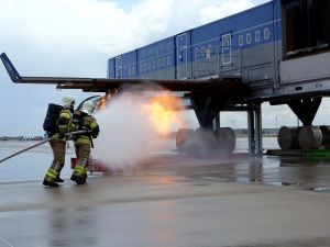 Zwei Kollegen der Flughafenfeuerwehr löschen einen Triebwerksbrand an der Brandsimulationsanlage.