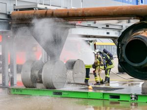 Zwei Kollegen der Flughafenfeuerwehr löschen einen Fahrwerkbrand an der Brandsimulationsanlage.