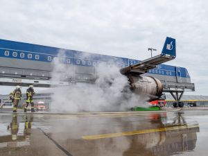 Zwei Kollegen der Flughafenfeuerwehr löschen einen Triebwerksbrand an der Brandsimulationsanlage.