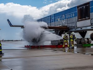 Zwei Kollegen der Flughafenfeuerwehr löschen einen Triebwerksbrand an der Brandsimulationsanlage.