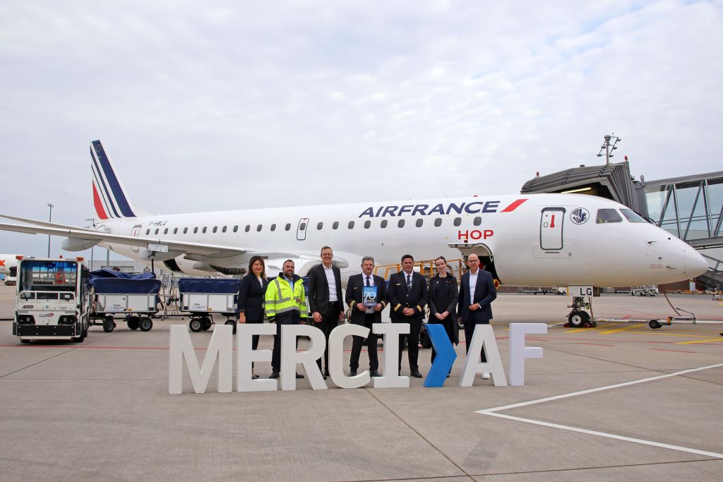 Vor einem Flugzeug der Air France stehen Männer und Frauen mit Buchstaben. Die Buchstaben bilden das Wort "MERCI AF" (AF steht für Air France).