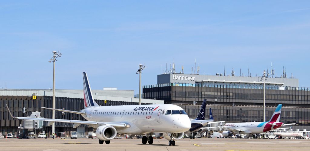 Ein Flugzeug der Air France auf dem Vorfeld des Hannover Airport. Im Hintergrund sieht man das Terminal und Flugzeuge Lufthansa und Eurowings.