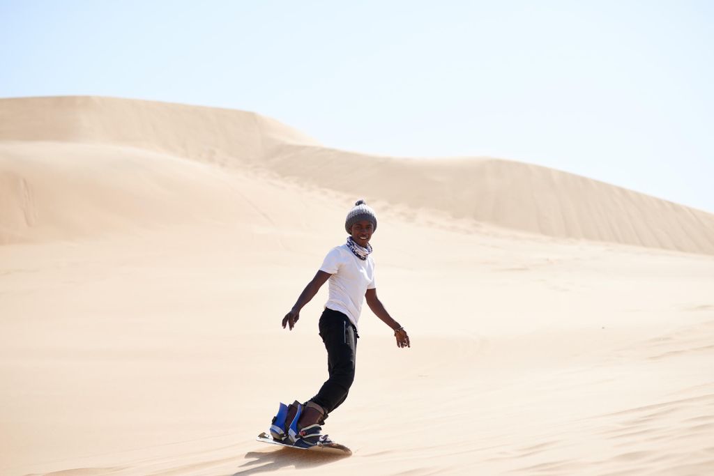 Junger Mann beim Sandboarden in der Wüste